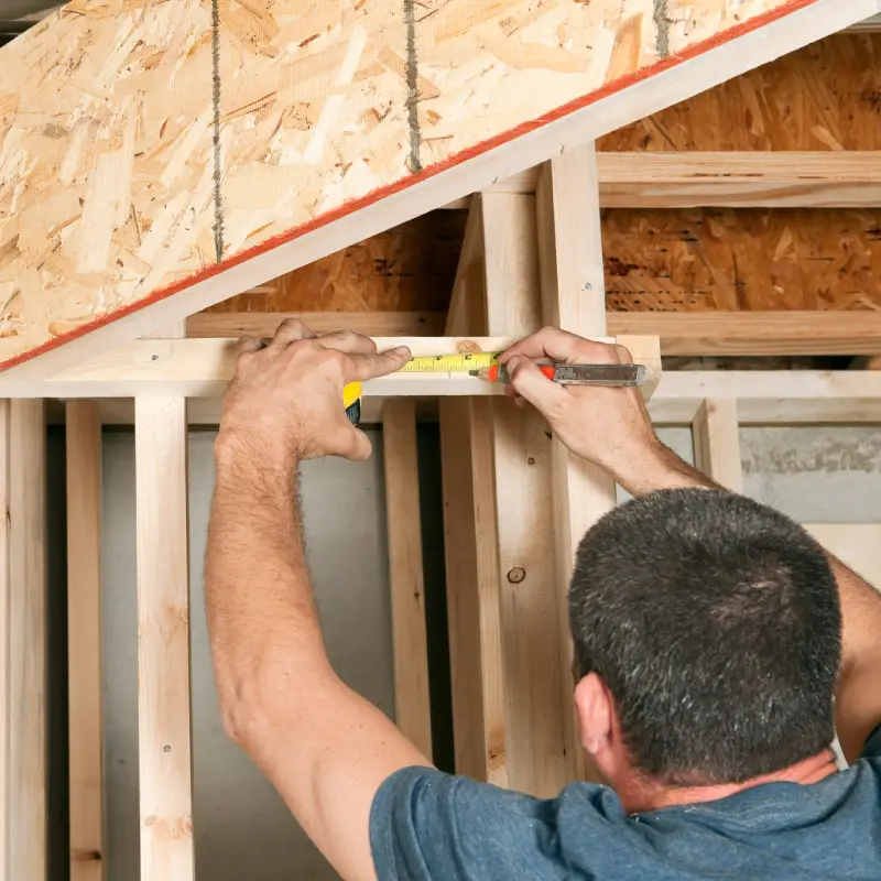 Carpenter measuring wooden frame with tape measure