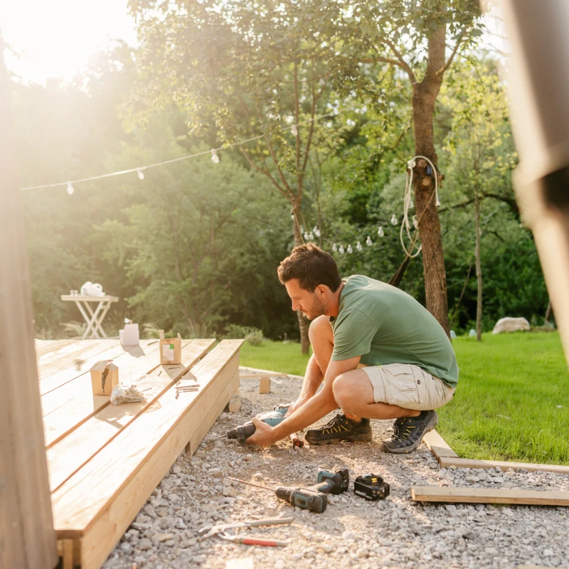 Man building wooden deck in backyard